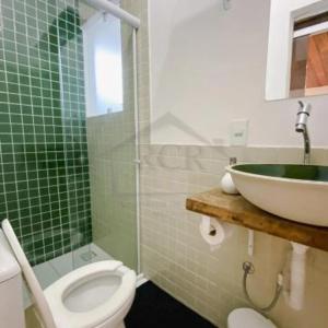 a green tiled bathroom with a toilet and a sink at Suítes Família Mateus in Ubatuba