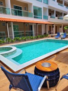 a pool at a hotel with chairs and a table at Pousada Concha Dourada in Maragogi