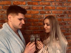 un hombre y una mujer sosteniendo una copa de champán en BIG BED JACUZZI, PRIVATE SAUNA AND CINEMA, en Dobrzewino