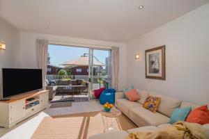 a living room with a couch and a flat screen tv at Ocean Serenity Apartments Whitianga in Whitianga