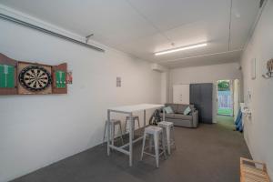 Habitación con mesa, taburetes y reloj en Ocean Serenity Apartments Whitianga en Whitianga