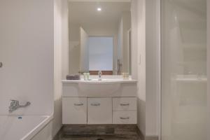 a white bathroom with a sink and a shower at Ocean Serenity Apartments Whitianga in Whitianga