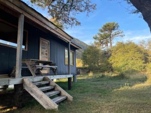 Cabaña azul con porche de madera y escaleras. en Araucanía Pura, en Malalcahuello