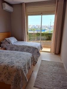 1 dormitorio con 2 camas y ventana grande en Havre de paix au bord de la mer, en Kenitra