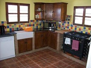 cocina con armarios de madera y estufa negra en Casa dos ponies, en Ríogordo