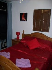 Schlafzimmer mit einem Bett mit roter Bettwäsche und einem Fenster in der Unterkunft Casa dos ponies in Ríogordo