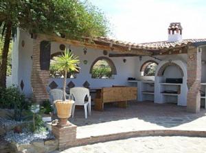 una cocina al aire libre con mesa y sillas en un patio en Casa dos ponies, en Ríogordo