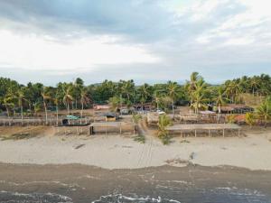 una playa de arena con palmeras y un complejo en Johnny Fiestas, en Las Lajas