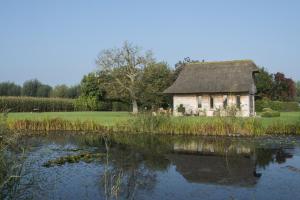 una casa vieja sentada junto a un estanque en Sint-Coryn, en Reninge