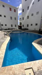 een groot blauw zwembad voor een gebouw bij Brand New Apt in PUNTA CANA. in Punta Cana