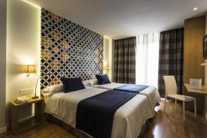 a hotel room with a bed and a table and chair at Hotel Comfort Dauro 2 in Granada