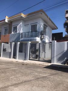 a white house with black shutters on a street at Modern Cozy 3BR Near Air-conditioned & Free Parking in Silang