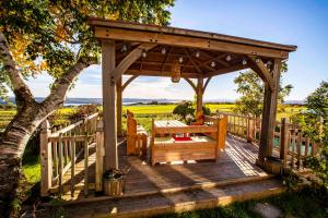 a wooden gazebo with a table and a bench at Bed and Breakfast Panorama in Saint-Laurent-de-l'ile d'Orleans