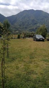 a car parked in a field with mountains in the background at Cabañas los 7 lagos in Panguipulli