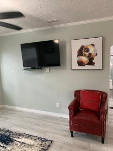sala de estar con silla roja y TV de pantalla plana en Sunshine Villa Two, en Jacksonville