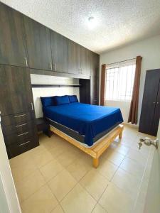 a bedroom with a blue bed and wooden cabinets at Condominio en Playa del Carmen c/alberca in Playa del Carmen