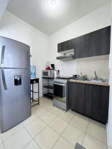 a large kitchen with a stainless steel refrigerator at Condominio en Playa del Carmen c/alberca in Playa del Carmen