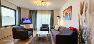a living room with a couch and two chairs and a tv at Wohnung-C-305 in Böhl