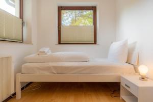 a white bedroom with a bed with a window at Wohnung-C-305 in Böhl