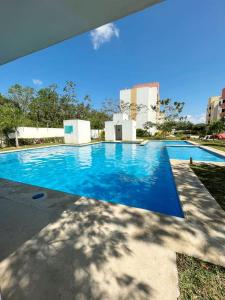 een groot zwembad met blauw water bij Condominio en Playa del Carmen c/alberca in Playa del Carmen