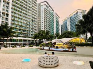 2 personnes assises sur la plage dans un complexe dans l'établissement Azure 2 Bedroom Pool View Balcony, à Manille