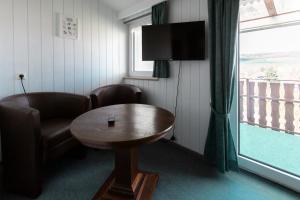 een kamer met een tafel, een stoel en een televisie bij Hotel Fröhlich-Höche in Uslar