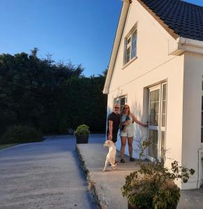 Happy Hill في يوغال: رجل وامرأة يقفان بجوار منزل به كلب