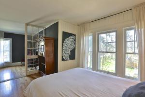 1 dormitorio con 1 cama blanca grande y ventanas en Cozy Grey Rabbit House 20mn from Mount Orford Ski Resort, en Ayers Cliff