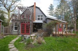 una casa con una puerta roja en un patio en Cozy Grey Rabbit House 20mn from Mount Orford Ski Resort, en Ayers Cliff