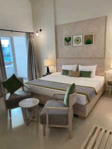 a bedroom with a large bed and a chair at Hotel Oviya in Vavuniya