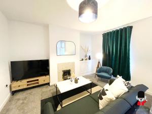 ウィガンにあるKozyGuru / Wigan / 2BR 4Beds / Newly Refurbished Stylish Holiday House / Close to Big Retail Park / UWNE034のソファとテレビのあるリビングルーム