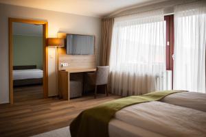 een hotelkamer met een bed en een bureau met een televisie bij Hotel Fröhlich-Höche in Uslar
