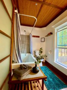 baño con bañera y mesa con planta en Cozy Grey Rabbit House 20mn from Mount Orford Ski Resort, en Ayers Cliff
