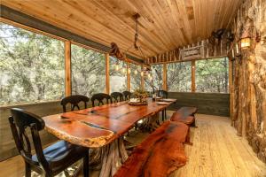 una gran mesa de madera en una habitación con ventanas en "Magical Treehouse" w spiral slide off the deck 350 acres on the Brazos River! Tubing! Petting Zoo!, en Weatherford