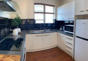 a kitchen with white cabinets and a black counter top at Yarrumla Beach Lodge in Somerton Park