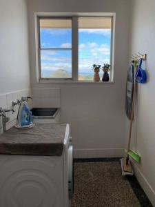 a kitchen with a window and a washing machine at Yarrumla Beach Lodge in Somerton Park