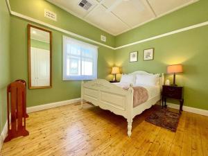 een slaapkamer met een wit bed en groene muren bij Jasmine Cottage in Katoomba