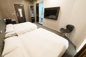 a hotel room with two beds and a flat screen tv at Welove meworld Inn in Taipei