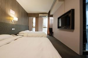 a hotel room with three beds and a flat screen tv at Welove meworld Inn in Taipei
