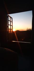 um pôr-do-sol visto através de uma janela de um edifício em Pousada Canto da Lua - charme e vista incrível em Carrancas