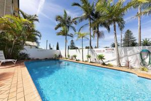 a swimming pool with palm trees in the background at Mirage 502 in Tuncurry