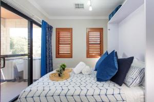 um quarto com uma cama com almofadas azuis e uma mesa. em Bambino 438 em Perth