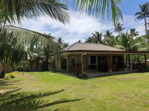 a house with a green yard and palm trees at Sunset Beach House Siargao in General Luna