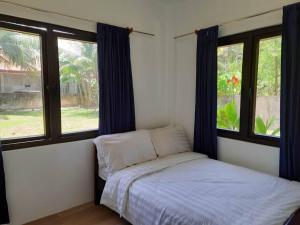 a small bedroom with a bed and two windows at Sunset Beach House Siargao in General Luna