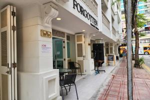 a building with a table and chairs on a street at Forgotten Hostel Silom in Bang Rak