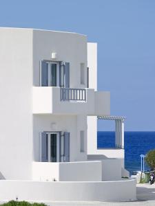 a white building with the ocean in the background at Garifalakis Comfort Rooms in Pollonia