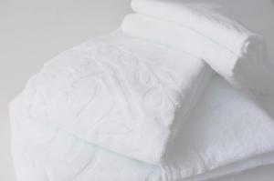 una pila de sábanas blancas en una cama en The Domain en Kochi
