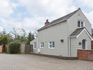 una casa blanca en una calle de ladrillo en Wisteria Cottage en New Milton