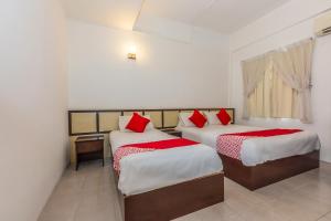 een kamer met 2 bedden en rode kussens bij Hash House Hotel in Melaka