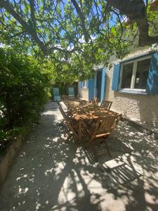 drewniany stół i krzesła przed budynkiem w obiekcie A l'ombre du figuier ! Maisonnette jardin / parking / proche mer w mieście Frontignan